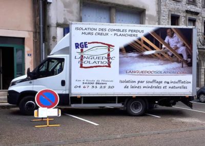 Camion avec le logo de Languedoc Isolation devant une maison